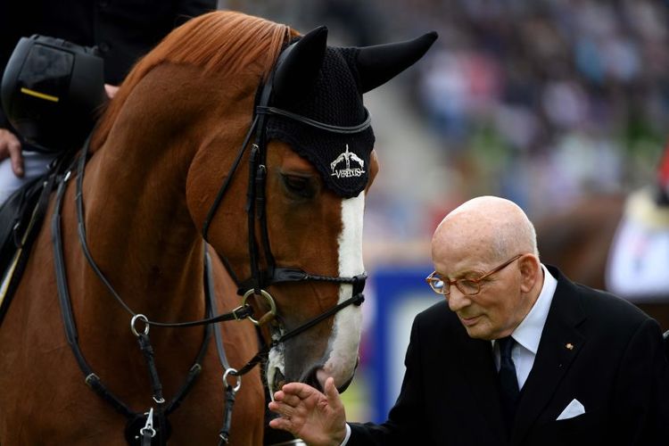 Hans Günter Winkler steht neben einem Pferd